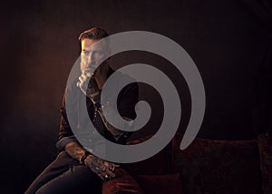 Portrait of an attractive bearded business man who is sitting in a dark room thinking about something