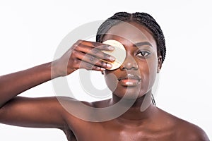 Portrait of attractive beautiful black african woman holding a make up sponge to her cheek, beauty skincare. cosmetics concept