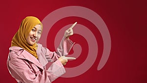 Portrait of attractive beautiful muslim teenage girl wearing hijab  smiling and pointing to the side with copy space, presenting