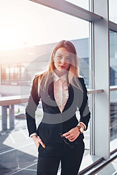 Portrait of attractive blonde wearing elegant formal suit standing in airport terminal