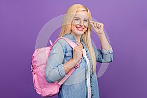 Portrait of attractive brainy cheerful girl touching specs going back to school isolated over bright violet purple color