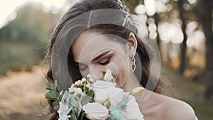 Portrait of attractive bride smiling and sniffing flowers at camera