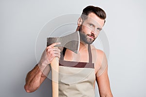 Portrait of attractive brutal guy wearing apron holding wooden ax cutting shaving beard isolated over light grey pastel