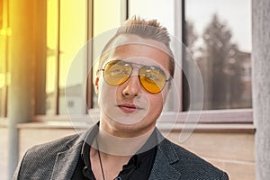 Portrait of attractive businessman of Caucasian appearance in sunglasses and jacket on street outdoor