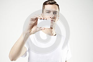 Portrait of attractive businessman holding blank business card, empty space for layout, with white background