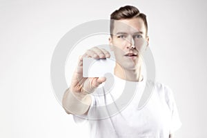 Portrait of attractive businessman holding blank business card, empty space for layout, with white background. Focus on card