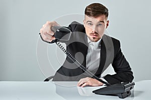 Portrait of attractive businessman holding telephone in his hand. This call is for you concept