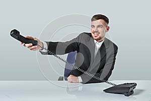 Portrait of attractive businessman holding telephone in his hand. This call is for you concept