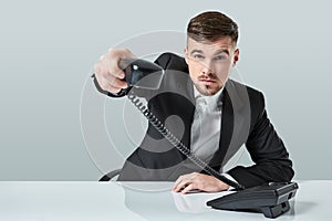 Portrait of attractive businessman holding telephone in his hand. This call is for you concept