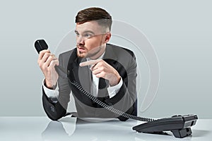 Portrait of attractive businessman holding telephone in his hand. This call is for you concept