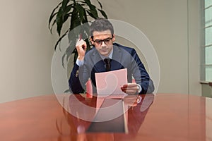 Portrait Of Attractive Businessman Reading Paper In Office