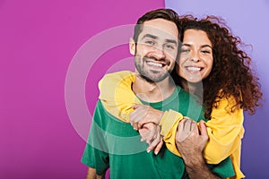 Portrait of attractive caucasian couple in colorful clothing smiling and hugging together