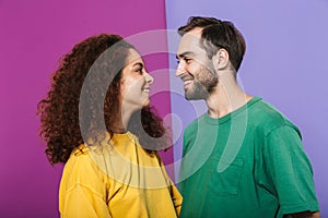 Portrait of attractive caucasian couple man and woman in colorful clothing smiling and looking at each other