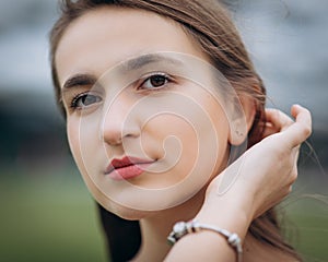 Portrait of attractive caucasian smiling woman brunette. Shot head and shoulders face skin hand hair looking at camera