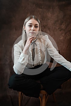 Portrait of caucasian woman wearing white blouse sitting at chair isolated dark background