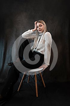 Portrait of caucasian woman wearing white blouse sitting at chair isolated dark background