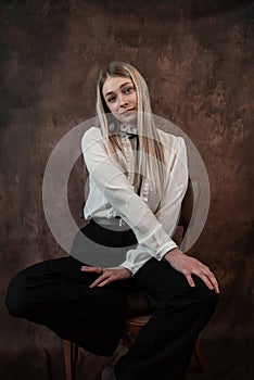 Portrait of caucasian woman wearing white blouse sitting at chair isolated dark background