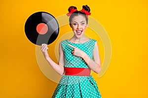 Portrait of attractive cheerful amazed girl holding in hands showing vinyl disc isolated on vibrant yellow color