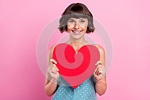 Portrait of attractive cheerful amorous girl holding heart shape  over pink pastel color background