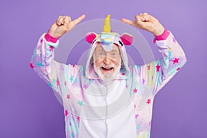 Portrait of attractive cheerful childish grey-haired man demonstrating kigurumi having fun  over violet purple