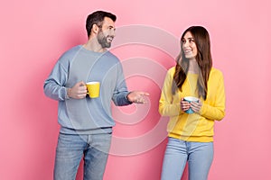 Portrait of attractive cheerful couple drinking latte cacao talking isolated over pink pastel color background