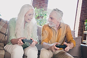 Portrait of attractive cheerful couple sitting on sofa playing game having fun free time at loft industrial interior