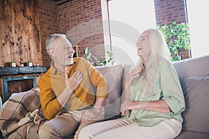 Portrait of attractive cheerful couple sitting on sofa talking having fun laughing at modern loft industrial interior