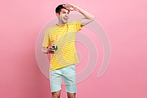 Portrait of attractive cheerful dreamy guy drinking beverage looking way rout isolated over pink pastel color background