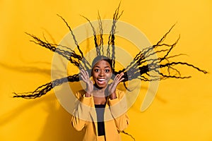 Portrait of attractive cheerful funky girl long hair flying good mood rest isolated on bright yellow color background