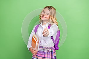 Portrait of attractive cheerful funny girl giving you caramel holding academic book isolated over green color background