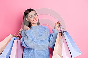 Portrait of attractive cheerful girl holding in hands bags store black friday isolated over pink pastel color background