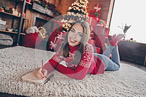 Portrait of attractive cheerful girl lying on carpet resting writing wish list surprise at loft industrial style