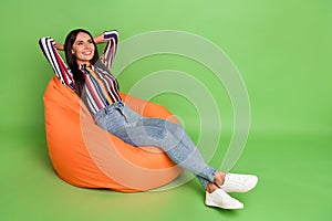 Portrait of attractive cheerful girl lying in soft bag chair resting free time isolated over green pastel color