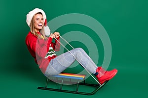 Portrait of attractive cheerful girl riding sledges having fun good mood isolated over green color background