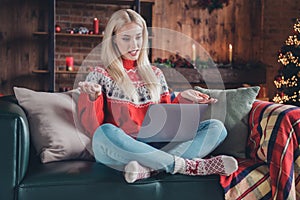 Portrait of attractive cheerful girl sitting on divan using laptop calling friend at home modern loft industrial
