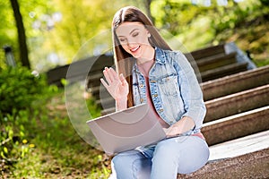 Portrait of attractive cheerful girl using laptop waving hi hello traveling blogging outdoor strolling fresh open air