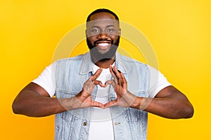 Portrait of attractive cheerful guy showing heart symbol affection isolated over bright yellow color background