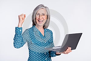 Portrait of attractive cheerful middle-aged lady using laptop rejoicing great success isolated over gray light pastel