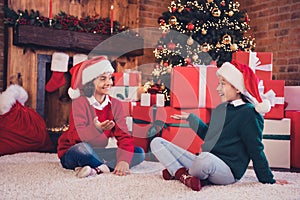 Portrait of attractive cheerful siblings spending newyear festal time santa helpers pile giftboxes at decorated loft