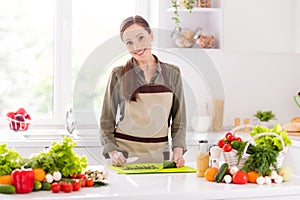 Portrait of attractive cheerful woman chopping fresh salad vegs farm products at home light white interior indoors