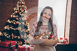 Portrait of attractive cheerful woman holding basket with bauble festal day time at decorated brick loft interior home