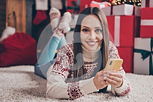 Portrait of attractive cheerful woman lying on carpet using device browsing web social network at decorated loft home