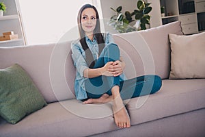 Portrait of attractive cheery dreamy long-haired woman sitting on divan resting thinking staying at home indoors