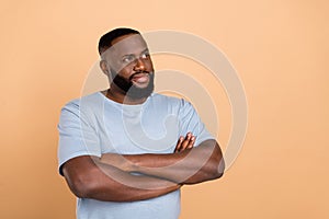 Portrait of attractive cheery minded guy fantasizing copy space folded arms isolated over beige pastel color background