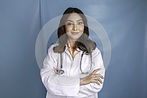 Portrait of an attractive confident female doctor, friendly smiling arms crossed wear white lab coat stethoscope isolated blue