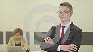 Portrait of a attractive confident young man in glasses and a beautiful suit looking in the camera crossing his arms in