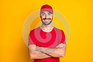 Portrait of attractive content virile cheerful guy mailman folded arms isolated over vibrant yellow color background