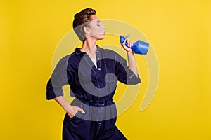 Portrait of attractive cool funny brown-haired girl holding pulverizer like gun isolated over bright yellow color