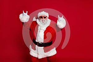 Portrait of attractive crazy cheerful childish Santa showing horn symbol having fun isolated over bright red color