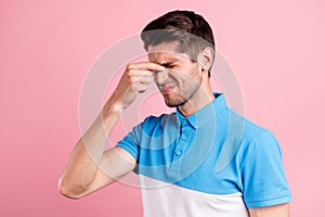 Portrait of attractive depressed brunette guy touching nose feeling bad spasm isolated over pink pastel color background
